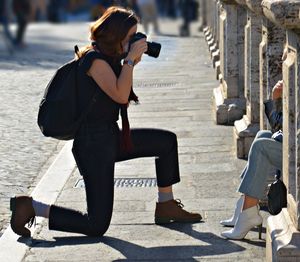 Side view of photographer photographing in city