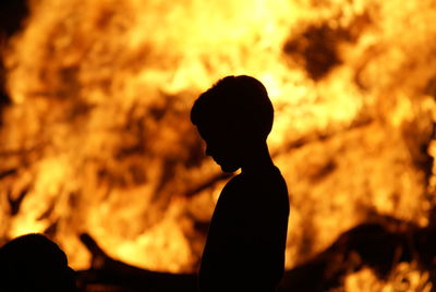 Silhouette man standing against fire