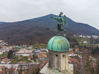 Statue by building against sky in city