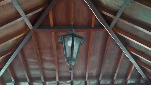 Low angle view of electric lamp hanging on ceiling of building