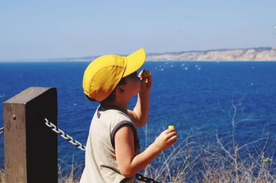 Boy blowing bubbles against clear sky