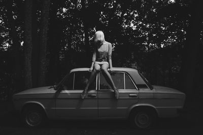 Rear view of a girl standing on car at night