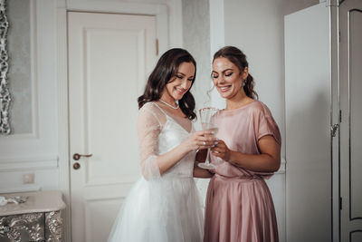 Bridesmaid and bride holding champagne flute