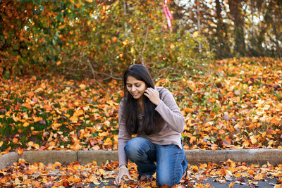 Woman kneeling on leaves during autumn