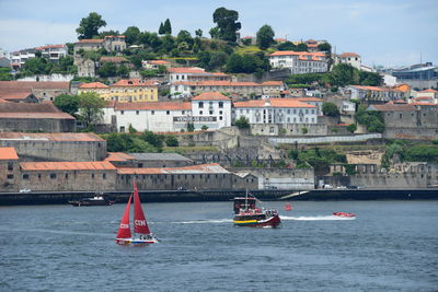 Sailboats sailing on sea by buildings in city