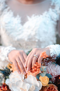 Midsection of bride with flowering plants