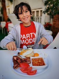 Portrait of a smiling boy having english breakfast food in an outside restaurant