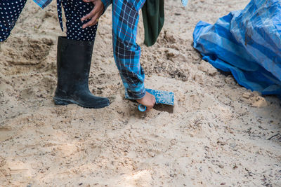 Low section of person cleaning sand at beach