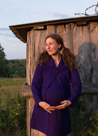 Young woman looking away while standing on wood