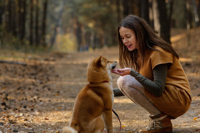 Beautiful woman walking shiba inu dog in fall forest. autumn mood