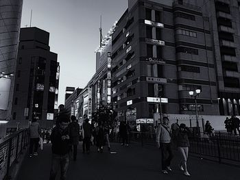 People walking on road in city against sky