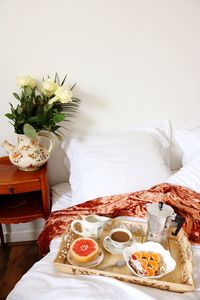 Food and drink in tray on bed at home