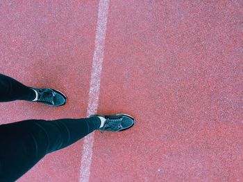 Low section of man standing on red shoes