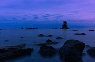 Rocks by sea against sky during sunset