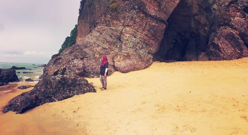 Full length of man on rock at beach against sky