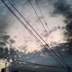 Low angle view of electricity pylon against cloudy sky