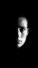 Close-up portrait of serious young woman against black background