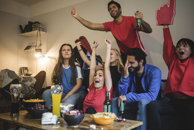 Multi-ethnic friends watching sport while sitting on sofa at home
