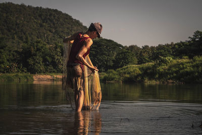 Man holding fishing net in lake