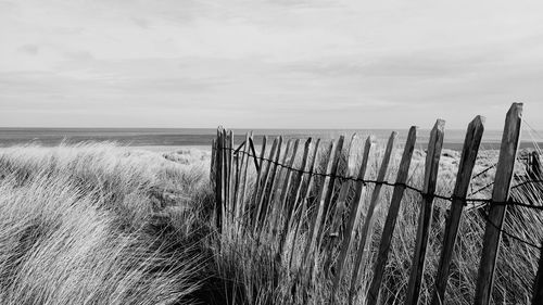 Barbed wire fence on beach against sky