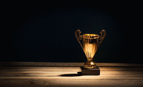 Close-up of illuminated lamp on table against black background