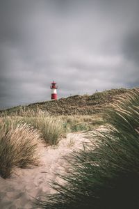 Lighthouse by sea against sky