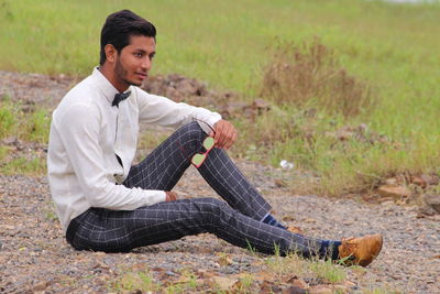 Full length of young man sitting on field