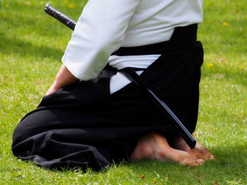 Low section of man with samurai sword on field