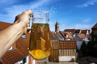 Cropped image of hand holding fresh drink against sky