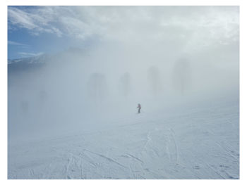 Rear view of man walking on snow covered landscape