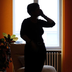 Side view of silhouette woman sitting on bed at home