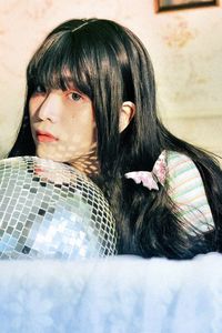 Portrait of young woman with disco ball lying on bed