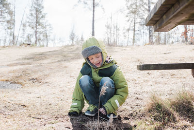 Young boy playing with plants whilst outside having a picnic