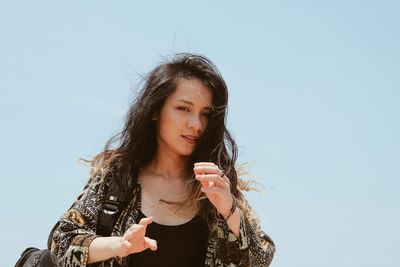 Portrait of young woman against clear sky