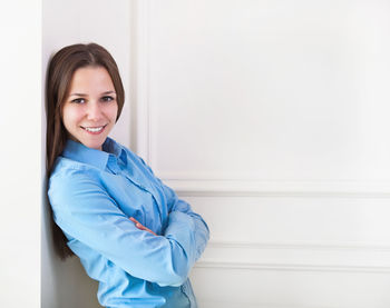 Portrait of a smiling young woman against wall