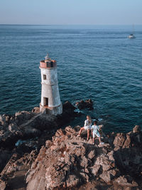 Lighthouse by sea against sky