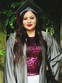Portrait of young woman wearing mortarboard and graduation gown