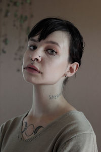 Portrait of young woman with piercing against wall
