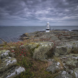 Lighthouse by sea against sky