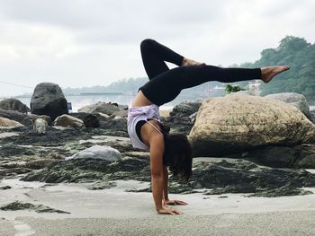 Woman doing handstand in city against sky