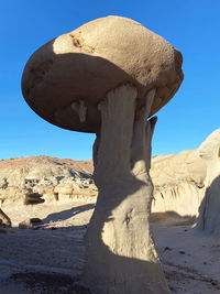 Low angle view of rock formation on land against clear blue sky