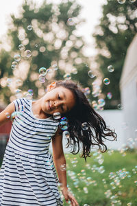 Diverse mixed race pre school age girl at home having fun playing with bubbles on a nice summer day