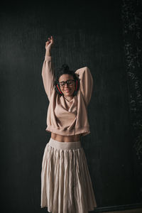 Portrait of young woman standing against wall