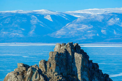 Scenic view of sea and rocks against blue sky