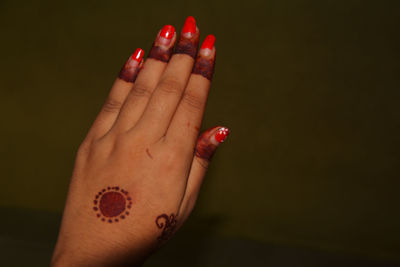 Close-up of woman hand with henna tattoo against colored background