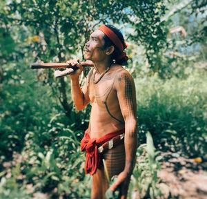 Side view of young woman standing against plants