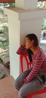 Young woman looking away while sitting outdoors