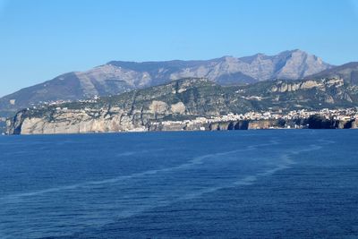 Scenic view of sea and mountains against clear blue sky