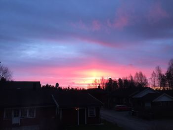 Silhouette of house against cloudy sky at sunset