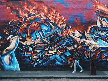 Full length of woman standing on graffiti wall